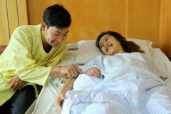 Vợ chồng sản phụ Phạm Thị Hồng Loan hạnh phúc bên cháu bé. (Ảnh: Trung Kiên/TTXVN) 