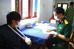 Cán bộ quân y thăm khám, kiểm tra sức khỏe cho bệnh nhân Mai Văn Miên (bên trái). (Ảnh: TTXVN phát)