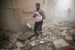 Người đàn ông bế một em bé sơ sinh chạy trên đường phố ở thị trấn Douma do phiến quân chiếm đóng, gần thủ đô Damascus. (Nguồn: Anadolu)