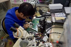 Một thợ sửa điện thoại tiến hành nâng cấp bộ nhớ trong iPhone. (Nguồn: CCTV)