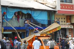 Lực lượng chức năng tiến hành tháo dỡ nhiều trường hợp nhà dân dựng mái che, biển hiệu chiếm vỉa hè đường Nguyễn Đình Chiểu (phường Đa Kao, quận 1). (Ảnh: Mạnh Linh/TTXVN)