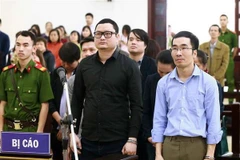 Bị cáo Trần Hữu Tiệp (áo đen) và các bị cáo khác trong vụ án thao túng giá chứng khoán. (Ảnh: Doãn Tấn/TTXVN)