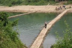 Đường vào Tà Mít, Tân Uyên, Lai Châu phải qua cây cầu tre nứa bắt qua sông Nậm Mu. Vào mùa mưa, cây cầu bị lũ cuốn trôi thì Tà Mít hoàn toàn cô lập với bên ngoài (Ảnh: Chí Bách/Vietnam+) 