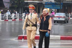 Nữ CSGT dẫn người dân qua ngã tư Hàng Bông (Ảnh: PV/Vietnam+)