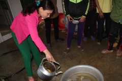 Nước giếng gia đình chị Thái Thị Hiên sau khi múc lên có màu vàng và bốc mùi dầu nồng nặc. (Ảnh: Phan Quân/TTXVN)