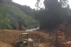 Nỗ lực san ủi đất đá sạt lở để thông tuyến Quốc lộ 40B. (Ảnh: Đoàn Hữu Trung/TTXVN)