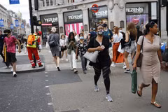 Người dân đeo khẩu trang phòng lây nhiễm COVID-19 khi di chuyển trên đường phố tại London, Anh. (Ảnh: AFP/TTXVN)