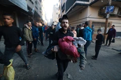 Chuyển em nhỏ bị thương trong vụ oanh tạc của Israel xuống thành phố Rafah, phía Nam Dải Gaza. (Ảnh: AFP/TTXVN)