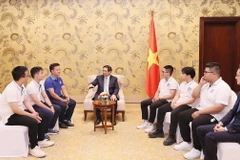 Thủ tướng Phạm Minh Chính chúc mừng các sinh viên xuất sắc giành giải thưởng tại COP28. (Ảnh: Dương Giang/TTXVN)