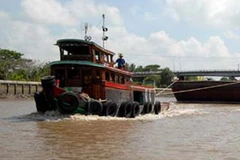 Tàu, thuyền tải trọng trên 500 tấn phải xếp hàng từng chiếc qua cầu kênh Chợ Gạo. (Ảnh: TTXVN)