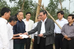 Ông Lê Hồng Anh trao tiền hỗ trợ cho các hộ có vườn cao su bị gãy đổ nặng tại xã Vĩnh Thủy, huyện Vĩnh Linh. (Ảnh: Hồ Cầu/TTXVN)