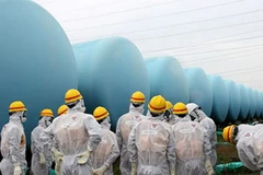 Nhân viên của Bộ điều chỉnh hạt nhân Nhật Bản gần các thùng chứa nước phóng xạ tại nhà máy điện Fukushima Daiichi. (Nguồn: EPA)