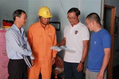 Cán bộ Điện lực hướng dẫn chủ nhà trọ giá bán điện theo quy định mới. (Ảnh: Phạm Cường/TTXVN)