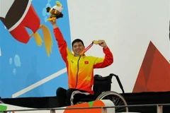 Vận động viên Võ Thanh Tùng tự hào giơ cao tấm Huy chương vàng thứ 3 tại Asian Para Games 2018. (Ảnh: Hải Ngọc/TTXVN)