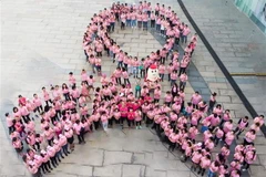 Xếp hình nơ hồng khổng lồ kêu gọi phụ nữ nâng cao nhận thức về bệnh ung thư vú. (Ảnh: TTXVN phát)