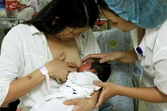 Nhân viên y tế Bệnh viện Phụ sản TW hướng dẫn sản phụ cho trẻ bú mẹ ngay giờ đầu sau khi sinh. (Ảnh: Dương Ngọc/TTXVN)