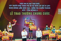 Chủ tịch UBND Thành phố Hồ Chí Minh Nguyễn Thành Phong cùng đại diện Ban tổ chức trao chiếc áo vàng chung cuộc cho vận động viên Loic Desriac. (Ảnh: Thanh Vũ/TTXVN)