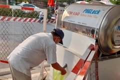 Người dân trong khu cách ly xếp hàng chờ lấy gạo từ cây ATM gạo. (Ảnh: Huyền Trang/TTXVN)