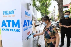 Người dân đến nhận khẩu trang từ cây ATM phát khẩu trang miễn phí trên phố Lạc Trung, Hà Nội. (Ảnh: Thành Đạt/TTXVN)