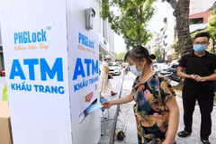 Người dân đến nhận khẩu trang từ cây ATM phát khẩu trang miễn phí trên phố Lạc Trung, Hà Nội. (Ảnh: Thành Đạt/TTXVN)