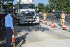 Lực lượng chức năng tiến hành kiểm soát tải trọng xe. (Ảnh: TTXVN)