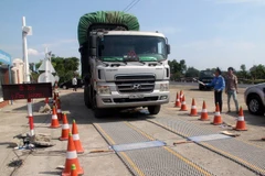 Lực lượng chức năng tiến hành kiểm tra tải trọng xe. (Ảnh: Thế Lập/TTXVN)