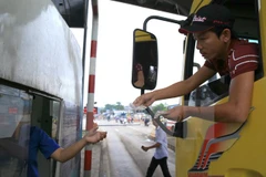 Lái xe dùng tiền mệnh giá 200-500 đồng mua vé qua trạm thu phí BOT tuyến tránh Biên Hòa gây ùn tắc kéo dài. (Ảnh: Sỹ Tuyên/TTXVN)