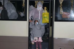 Các công dân xuống xe làm thủ tục vào khu tập trung. (Ảnh minh họa: Thanh Hải/TTXVN)