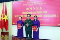 Thượng tá Ngô Nam Cường, Chỉ huy trưởng Bộ Chỉ huy Quân sự tỉnh Thừa Thiên-Huế trao quyết định tuyển dụng và trao quân hàm cho thân nhân liệt sỹ. (Ảnh: TTXVN phát)