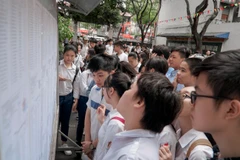 Thí sinh xem số báo danh và phòng thi tại điểm thi Trường Trung học phổ thông Việt Đức. (Ảnh: Minh Hiếu/Vietnam+)