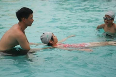 Huấn luyện viên hướng dẫn học sinh kỹ năng cơ bản để học bơi. (Ảnh: Thanh Tùng/TTXVN)