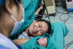 Khoảnh khắc hạnh phúc tột cùng của chị Nguyễn Thị Mỹ Hạnh khi ngắm nhìn đứa con trai mới chào đời mạnh khỏe. (Ảnh: Minh Sơn/Vietnam+)