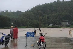 Lực lượng chức năng huyện Đồng Xuân gắn biển cảnh báo và cử lực lượng chức năng chốt chặn tại một tuyến đường bị ngập trong nước lũ. (Ảnh: TTXVN phát)