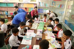 Học sinh trường tiểu học Nơ Trang Lơng đọc sách từ chương trình Tủ sách Đinh Hữu Dư trao tặng. (Ảnh: Hoài Thu/TTXVN)
