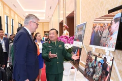 Thứ trưởng Bộ Quốc phòng Hoàng Xuân Chiến và Phó Tổng Thư ký Liên hợp quốc Jean-Pierre Lacroix cùng các đại biểu xem triển lãm ảnh về phụ nữ với hoạt động gìn giữ hòa bình LHQ. (Ảnh: Trọng Đức/TTXVN)