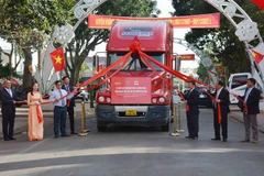 Các đại biểu thực hiện nghi thức kéo dải lụa đỏ cho xe chạy xuất khẩu container macca Krông Năng đầu tiên. (Ảnh: Hoài Thu/TTXVN)
