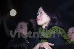 Chị Mai Hoa, vợ Trần Lập đứng thu mình ở một góc nhỏ phía khán giả lắng nghe những bài hát của anh. (Ảnh: Minh Sơn/Vietnam+)