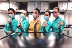 Đội ngũ tiếp viên Vietnam Airlines luôn mang đầy đủ đồ bảo hộ khi phục vụ trên chuyến bay nhằm phòng chống dịch bệnh COVID-19. (Ảnh: CTV/Vietnam+)