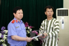 Chánh văn phòng Viện Kiểm sát Nhân dân Tối cao Nguyễn Việt Hùng trao quyết định tạm đình chỉ thi hành án đối với ông Nguyễn Thanh Chấn. (Ảnh: Doãn Tấn/TTXVN) 