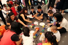 Cậu bé William “góp ý” với chị sau khi đã hoàn thành chiếc mặt nạ của mình.(Ảnh: Doãn Đức/Vietnam+)