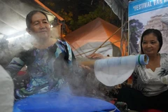 Các nghệ nhân biểu diễn công đoạn tráng bánh tại lễ hội. (Ảnh: Thanh Tân/TTXVN)