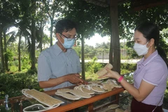 Anh Phạm Văn Đoàn giới thiệu các sản phẩm làm từ xơ mướp với khách hàng. (Ảnh: Hoàng Nhị/TTXVN)