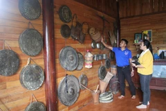 Anh Siêng giới thiệu về các nhạc cụ, vật dụng tại khu trưng bày của mình cho một du khách. (Ảnh: Đinh Hương/TTXVN)