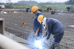 Các công nhân vẫn tiếp tục thi công và đón Tết Dương lịch 2022 ngay trên công trường Cầu Vĩnh Tuy 2. (Ảnh: Hoàng Hiếu/TTXVN) 