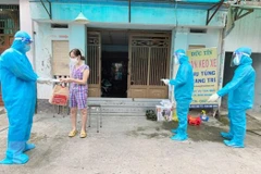 Nhân viên y tế trạm y tế lưu động phường 25, quận Bình Thạnh phát túi thuốc cho F0 điều trị tại nhà. (Ảnh: Đinh Hằng/TTXVN) 