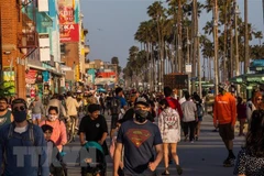 Người dân đi dạo trên bãi biển ở Mỹ. (Ảnh: AFP/TTXVN)