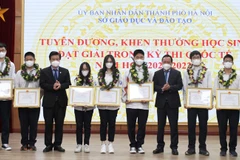 Thứ trưởng Bộ Giáo dục và Đào tạo Nguyễn Hữu Độ và Phó Bí thư Thành ủy Hà Nội Nguyễn Văn Phong trao Bằng khen của Ủy ban Nhân dân thành phố cho các học sinh đạt Huy chương Vàng. (Nguồn: Báo Hà Nội mới)