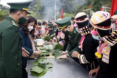 Bộ đội Biên phòng cùng với bà con nhân dân xã Huổi Luông, huyện Phong Thổ gói bánh chưng xanh tặng cho hộ nghèo. (Ảnh: Đinh Thùy/TTXVN)