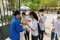  Thanh niên tình nguyện xã Minh Tân cung cấp nước mía miễn phí cho thí sinh và người nhà thí sinh. (Ảnh: TTXVN phát)