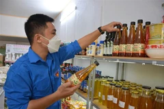 Anh Vũ Minh Ngọc kiểm tra sản phẩm giấm mơ trà xanh tại cửa hàng nông nghiệp sạch thành phố Nam Định. (Ảnh: Công Luật/TTXVN)